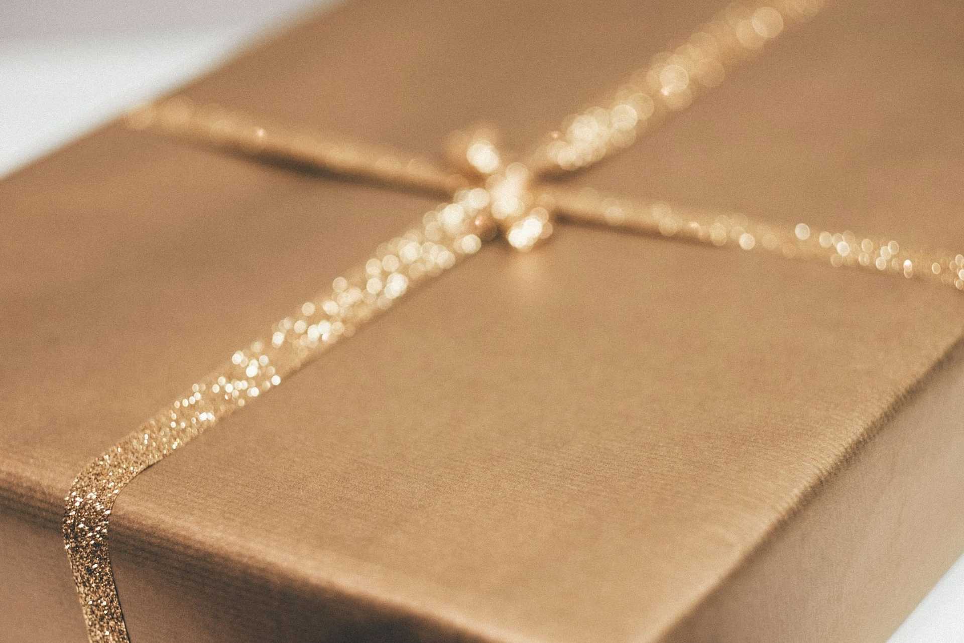 Gold-wrapped gift box with a sparkly ribbon, close-up.